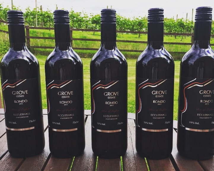Five bottles of Grove Estate Rondo with the vineyard behind